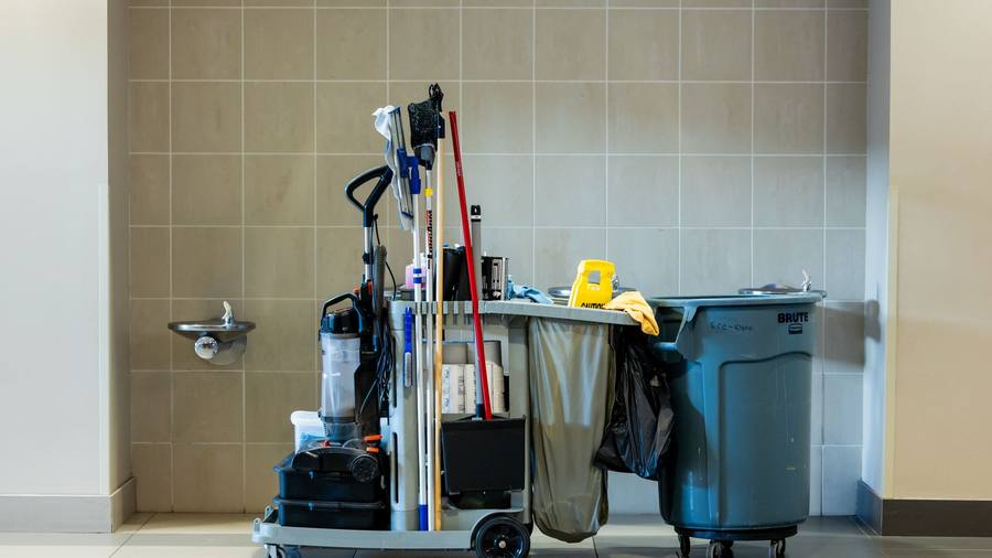 A cleaning cart in a bright tiled corridor